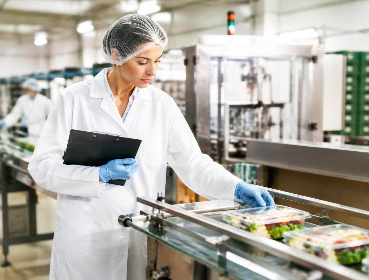 Food safety auditor inspecting packaged products on a production line